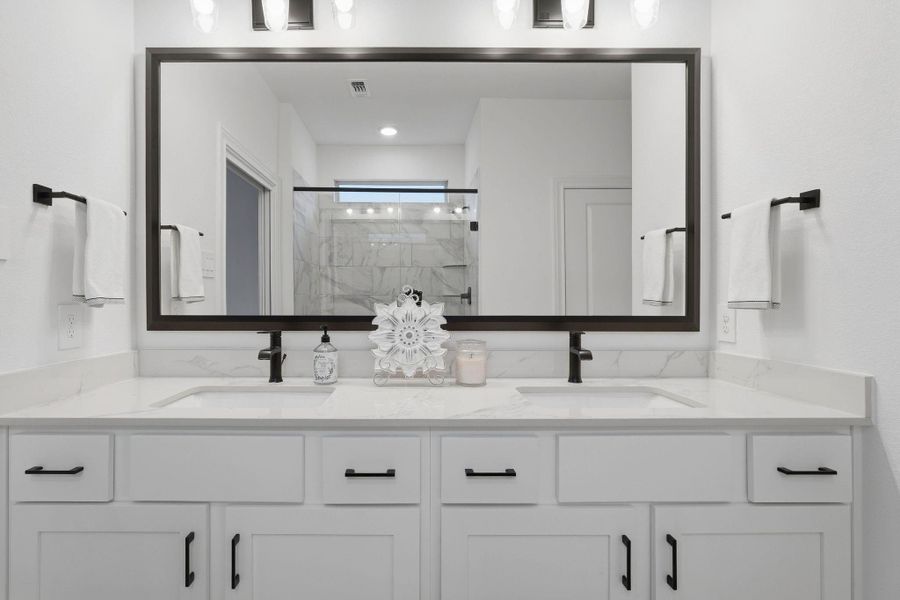 A double-sink vanity with bold black fixtures adds contrast and style, paired with clean white cabinetry and soft lighting.