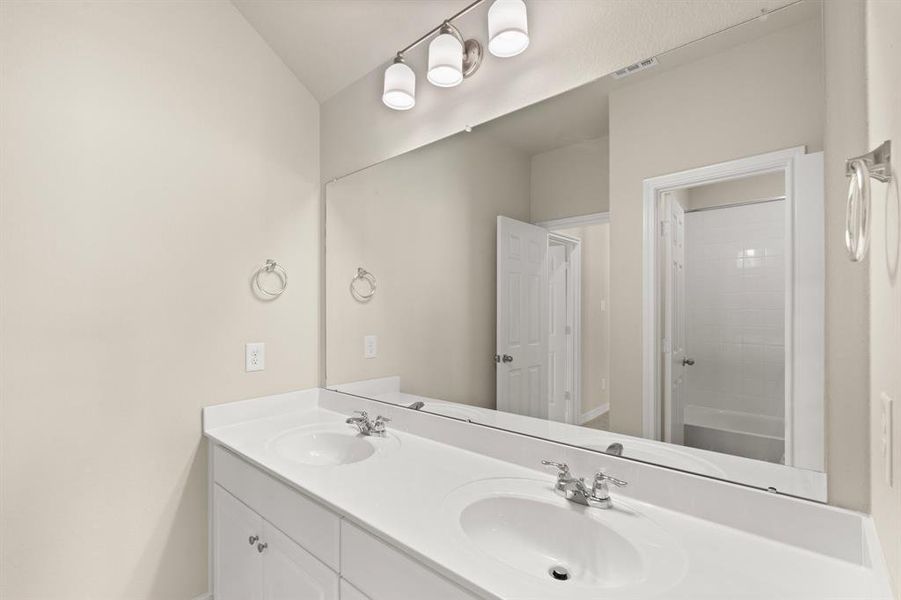 The secondary bath features tile flooring, white cabinetry and light countertops and a shower/tub combo. Perfect for accommodating any visiting family and friends.