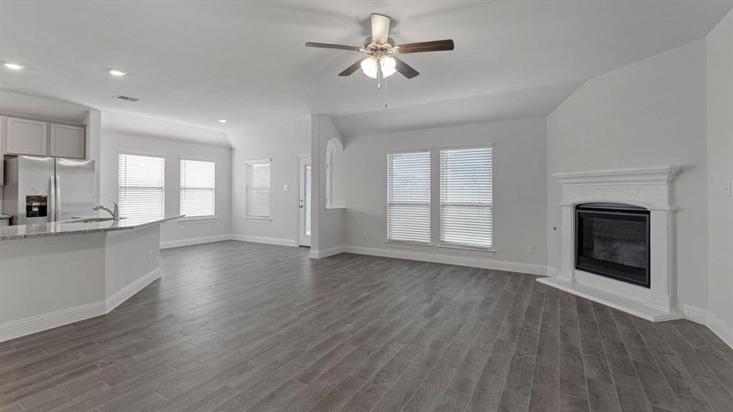 Unfurnished living room featuring a glass covered fireplace, a ceiling fan, wood tiled floors, healthy amount of natural light, and recessed lighting