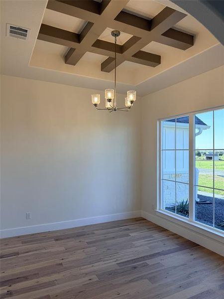 Office off of the front of the home featuring coffered ceiling, suspended lighting, and vinyl plank wood-style floors Office off of the front of the home featuring coffered ceiling, suspended lighting, and vinyl plank wood-style floors