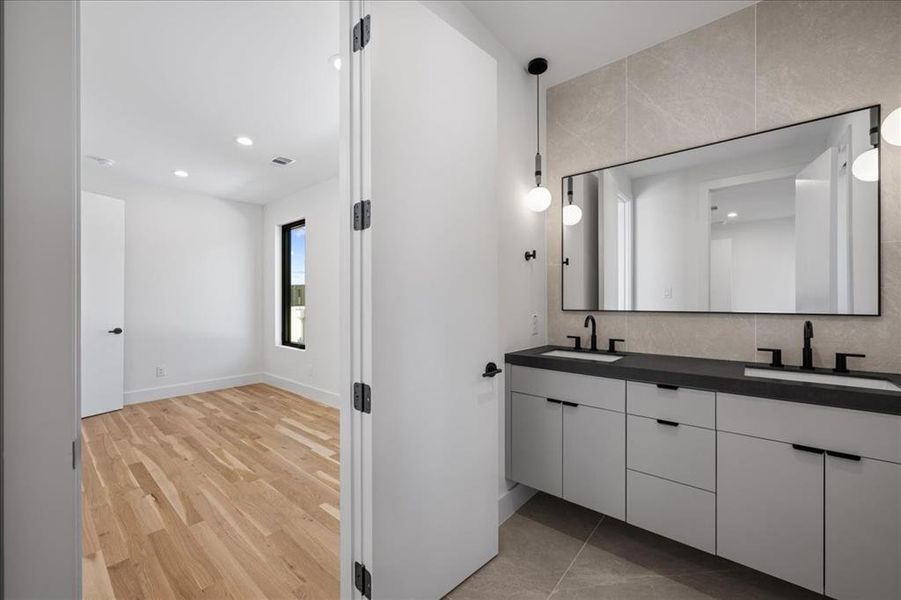 Jack & Jill bathroom with double vanity, recessed lighting, tasteful backsplash, and light wood-style floors Jack & Jill bathroom with double vanity, recessed lighting, tasteful backsplash, and light wood-style floors