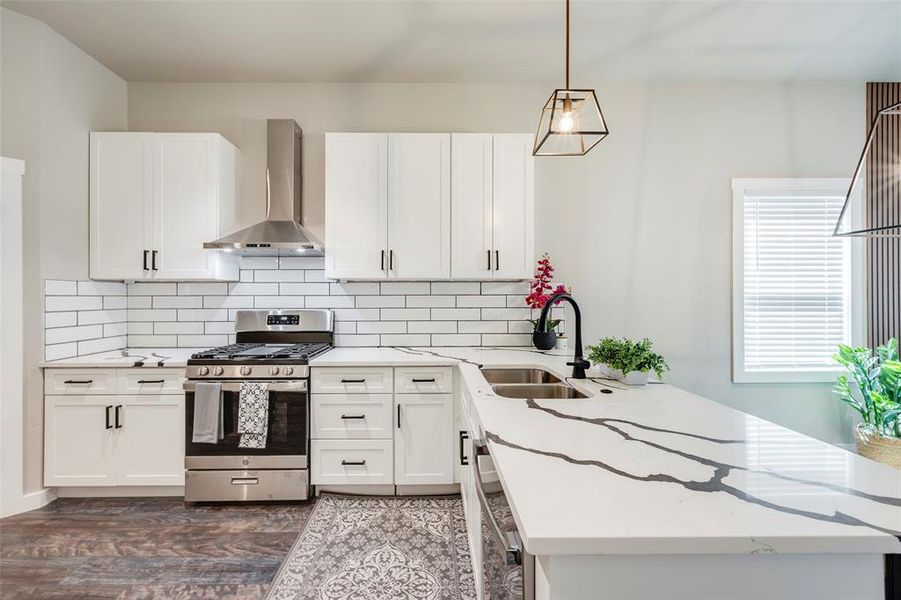 Kitchen with stainless steel appliances, wall chimney range hood, white cabinetry, and light stone countertops