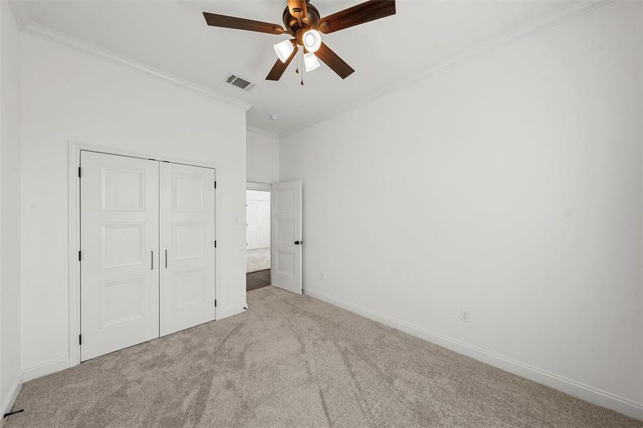 Unfurnished bedroom featuring carpet flooring, crown molding, a closet, and ceiling fan Unfurnished bedroom featuring carpet flooring, crown molding, a closet, and ceiling fan