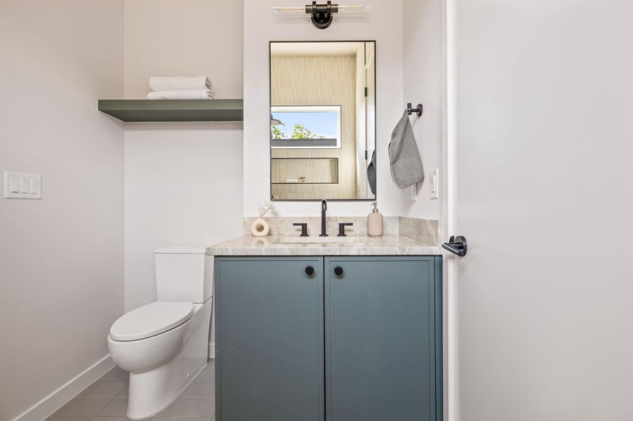 A modern vanity with stone counters and flat-panel cabinetry defines this elegant powder room. A modern vanity with stone counters and flat-panel cabinetry defines this elegant powder room.