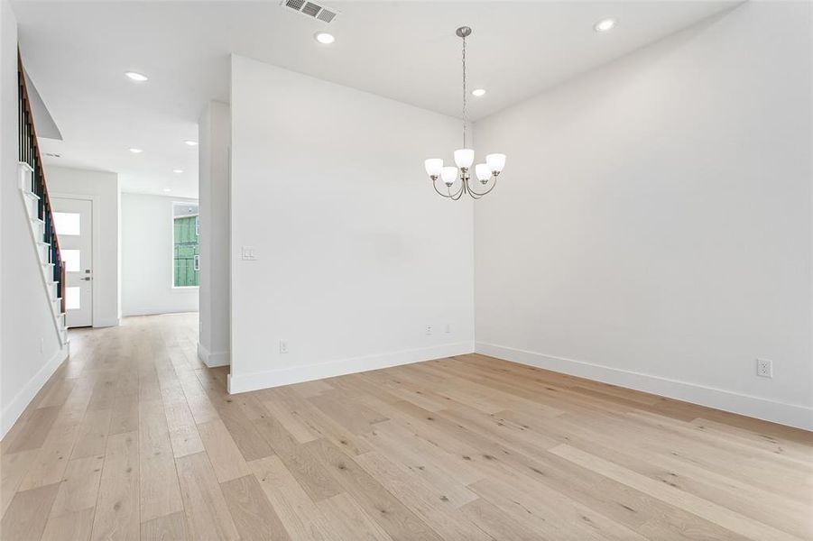 Spare room with a notable chandelier and light hardwood / wood-style floors