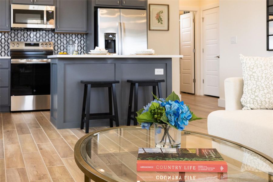 Kitchen with stainless steel appliances, light wood-style floors, light countertops, and a kitchen bar