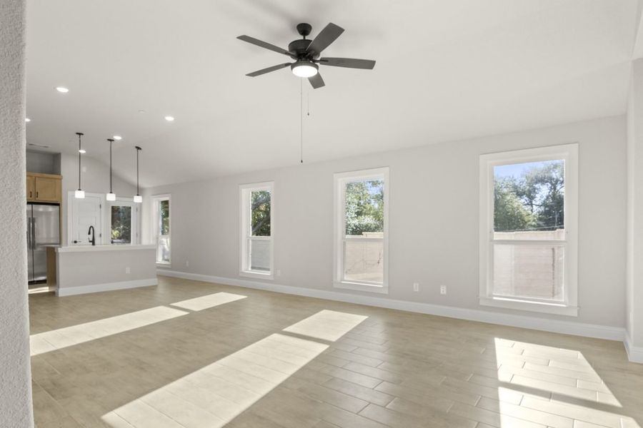 Image of a one story home living room with light wood-like flooring and light grey painted walls with two large windows and a ceiling fan Image of a one story home living room with light wood-like flooring and light grey painted walls with two large windows and a ceiling fan