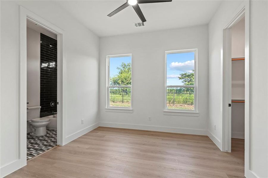 Unfurnished bedroom featuring light wood-style flooring, ceiling fan, and ensuite bathroom Unfurnished bedroom featuring light wood-style flooring, ceiling fan, and ensuite bathroom