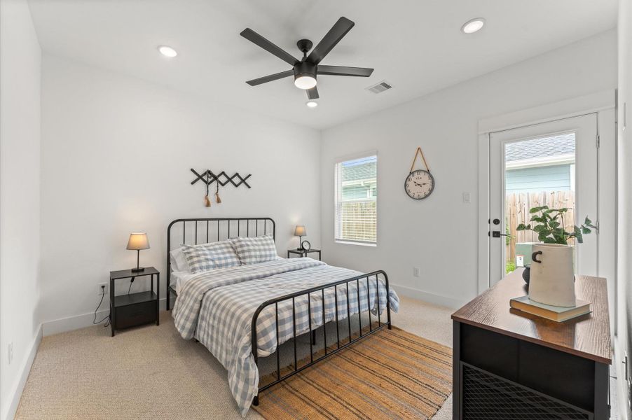 Stylish and versatile secondary bedroom situated on the first floor, offering direct access to the backyard through elegant glass patio door. This sunlit space features warm-toned flooring, soft neutral walls, and generous room for a queen-sized bed and additional furnishings. Outdoor access enhances the room’s appeal for relaxation, remote work, guest room.