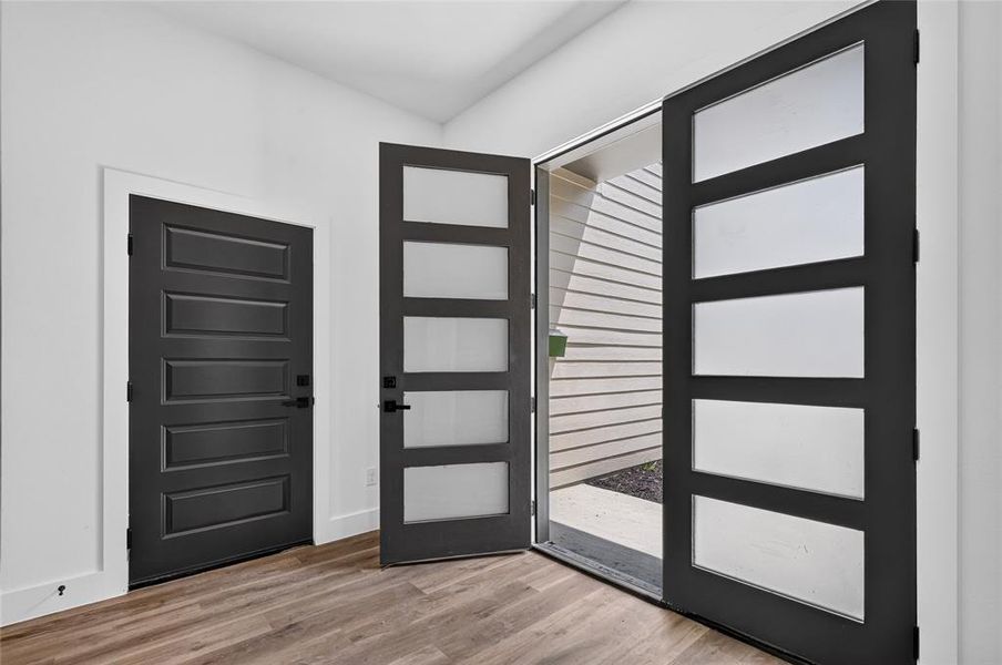 Entryway featuring a modern black door with frosted glass panels and a solid black panel door Entryway featuring a modern black door with frosted glass panels and a solid black panel door