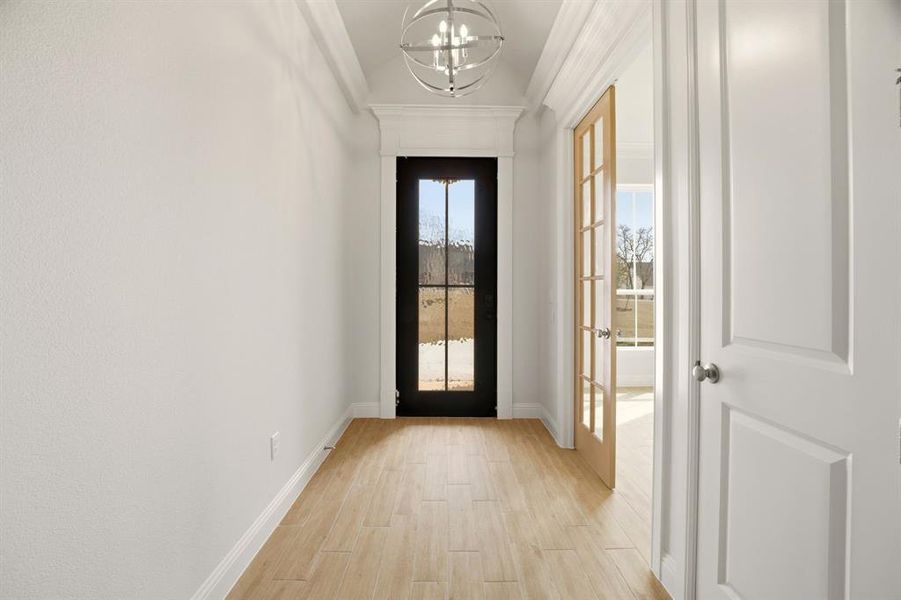 Doorway to outside with wood finished floors, hanging lights, and vaulted ceiling Doorway to outside with wood finished floors, hanging lights, and vaulted ceiling