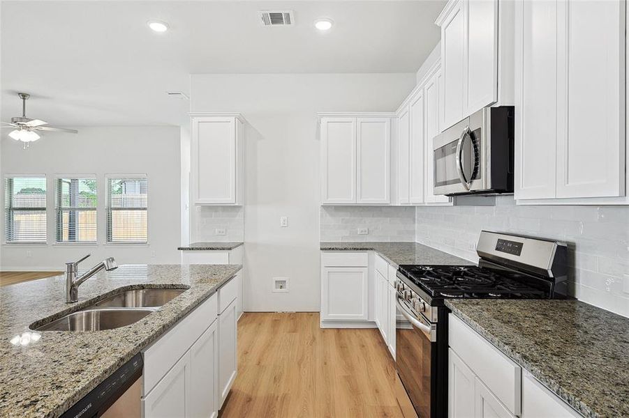 Kitchen featuring ceiling fan, stainless steel appliances, light wood-type flooring, backsplash, and sink