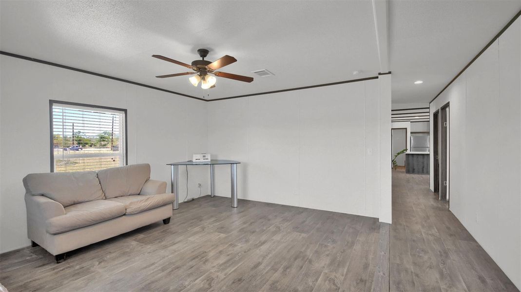 Living area featuring wood finished floors, ceiling fan, and crown molding