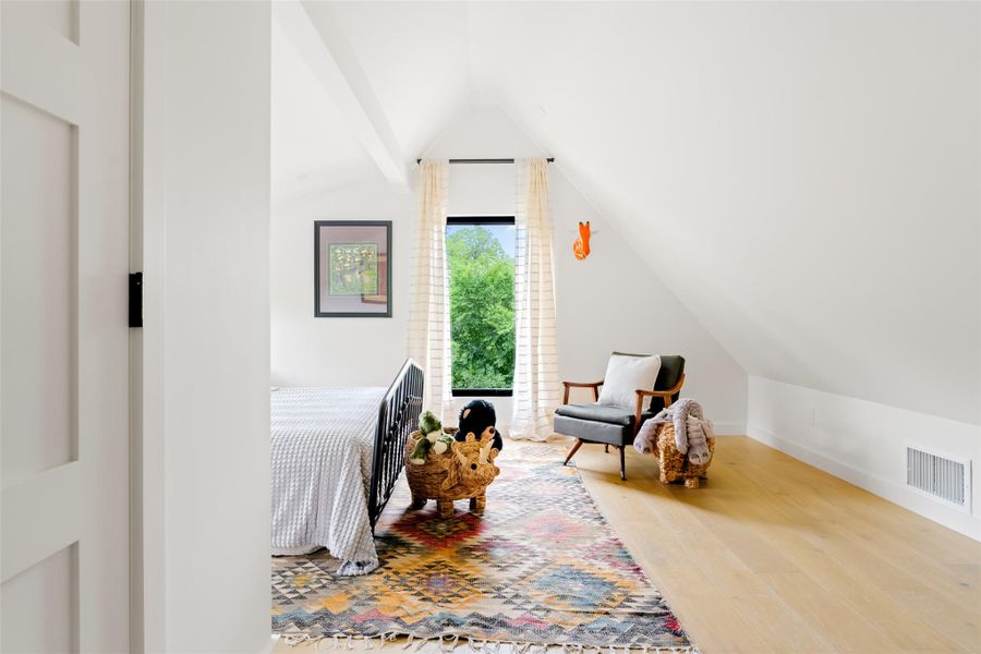 Bedroom with visible vents, baseboards, lofted ceiling, and wood finished floors
