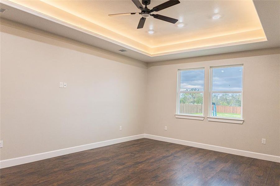 Empty room featuring dark wood-style flooring, a tray ceiling, a ceiling fan, and recessed lighting Empty room featuring dark wood-style flooring, a tray ceiling, a ceiling fan, and recessed lighting