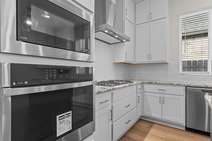 Gourmet kitchen with sleek stainless-steel appliances, built-in microwave and oven, gas cooktop, and abundant cabinet storage.  What I like is the Pot and Pans Cabinets!  Birch cabinets with 42-inch uppers, pot and pan drawers beneath built in stainless steel gas  cooktop
