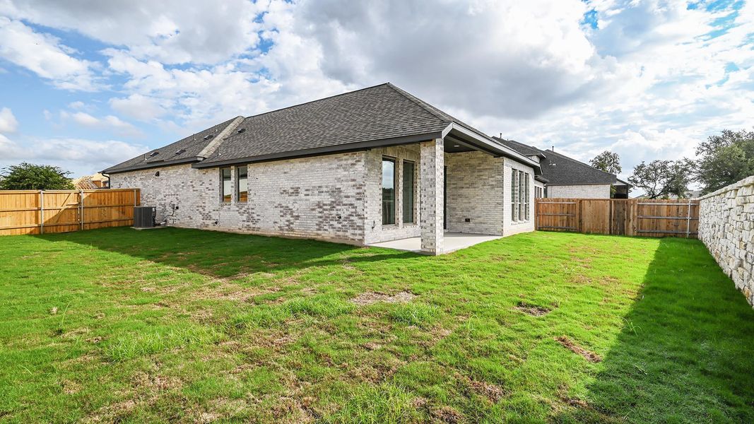 Rear view of house featuring a patio area, a fenced backyard, brick siding, and a shingled roof