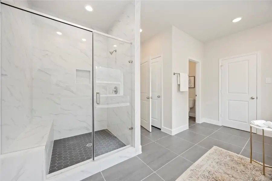 The bathroom's smart configuration provides access to one of two primary closets, a discreet water closet with a private commode, and a separate linen closet, contributing to the home's abundant storage options.