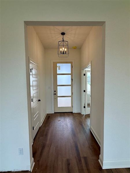 Doorway featuring a chandelier and wood finished floors