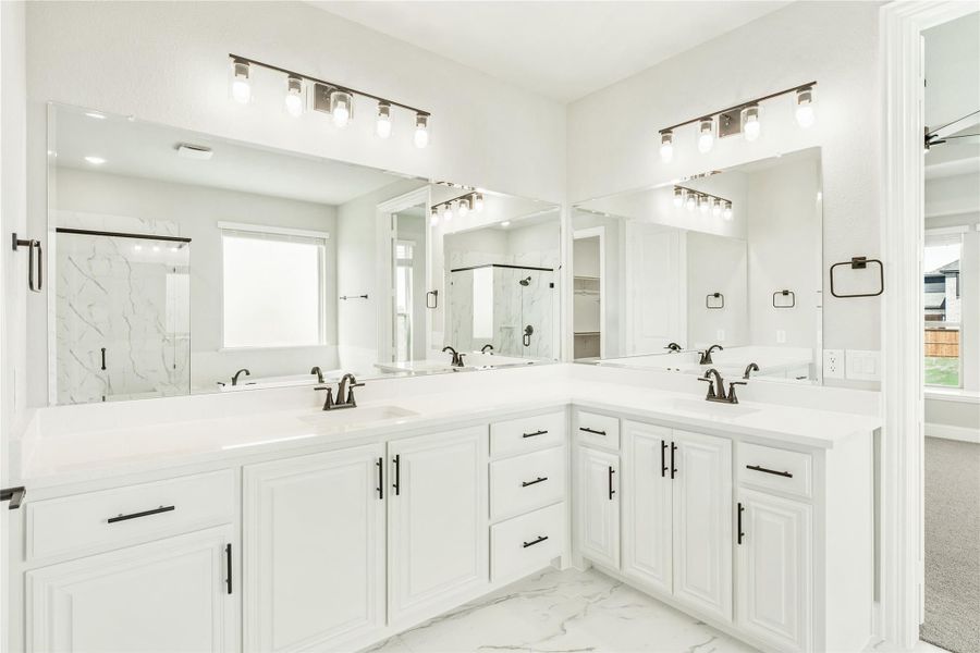 Master bathroom with dual vanities, white cabinets, quartz countertops, and large mirrors with overhead lighting Master bathroom with dual vanities, white cabinets, quartz countertops, and large mirrors with overhead lighting