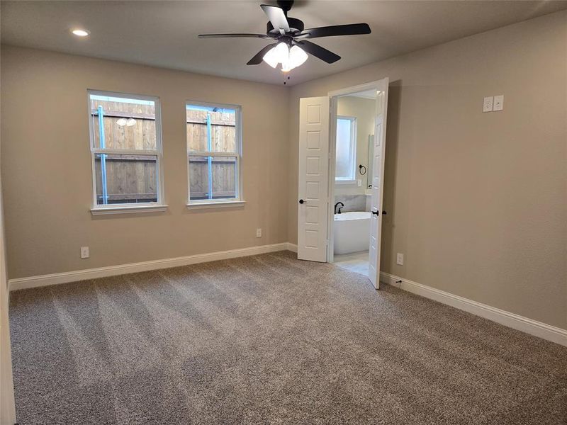 Carpeted empty room with baseboards and ceiling fan Carpeted empty room with baseboards and ceiling fan
