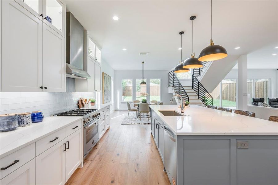 Kitchen with white cabinetry, light stone counters, decorative light fixtures, stainless steel appliances, and recessed lighting Kitchen with white cabinetry, light stone counters, decorative light fixtures, stainless steel appliances, and recessed lighting