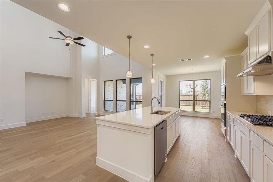 Kitchen with recessed lighting, pendant lighting, white cabinetry, light wood finished floors, and open floor plan Kitchen with recessed lighting, pendant lighting, white cabinetry, light wood finished floors, and open floor plan