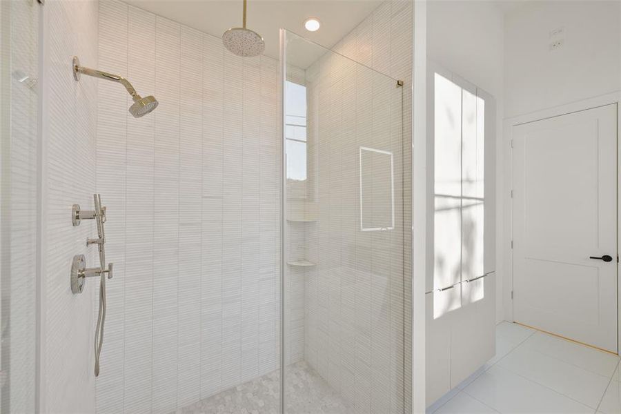 You will love this custom seamless glass rain shower with handheld wand all supplied by Ferguson's. The custom tile, glass wall and linear drain elevate the space.