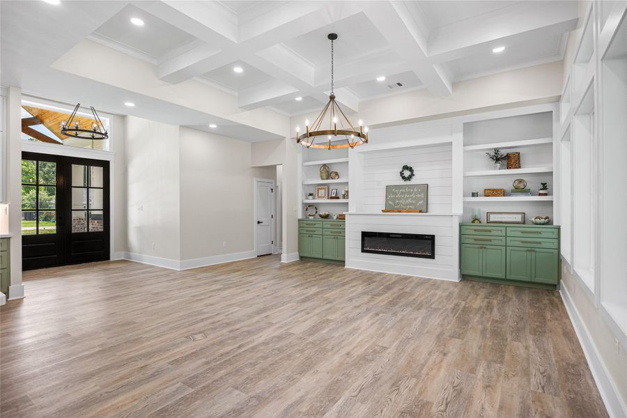 Family Room offers high coffer ceilings with recessing lighting. a modern electric fireplace, and beautiful finishes.