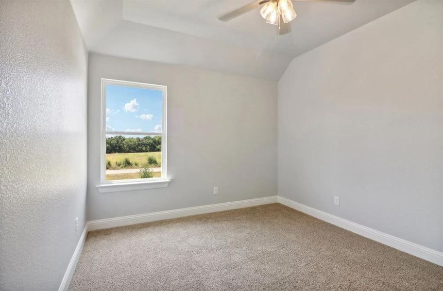 Carpeted empty room featuring lofted ceiling and ceiling fan