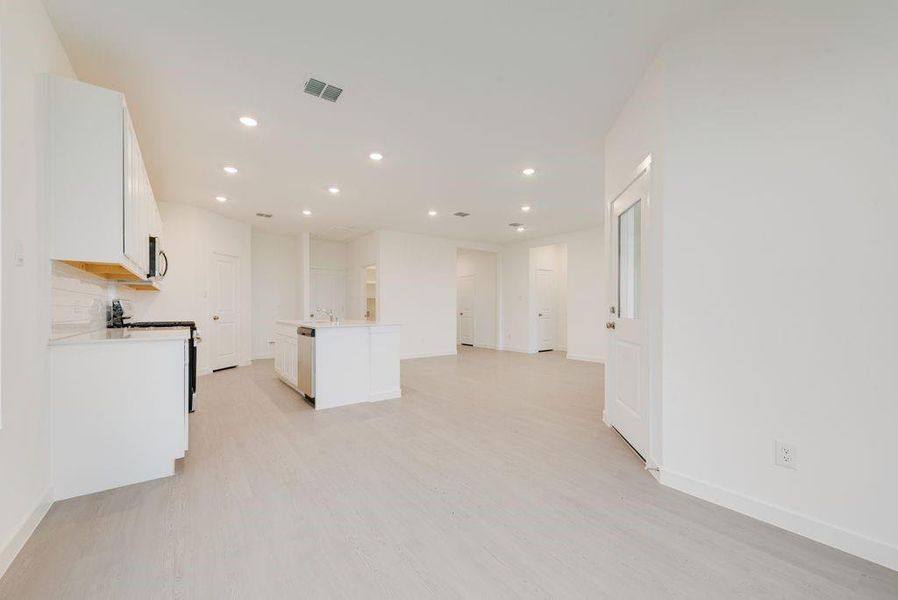 Kitchen with white cabinetry, stainless steel appliances, light wood-type flooring, recessed lighting, and a kitchen island with sink Kitchen with white cabinetry, stainless steel appliances, light wood-type flooring, recessed lighting, and a kitchen island with sink