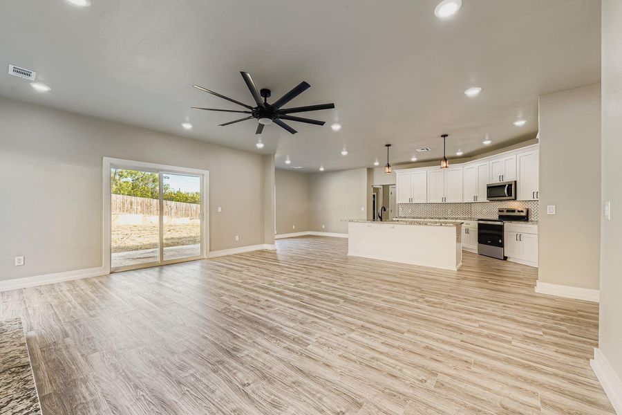 Unfurnished living room featuring light wood-style flooring, ceiling fan, and recessed lighting