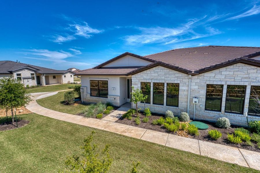 Ranch-style house featuring a front lawn, a tile roof, and stone siding