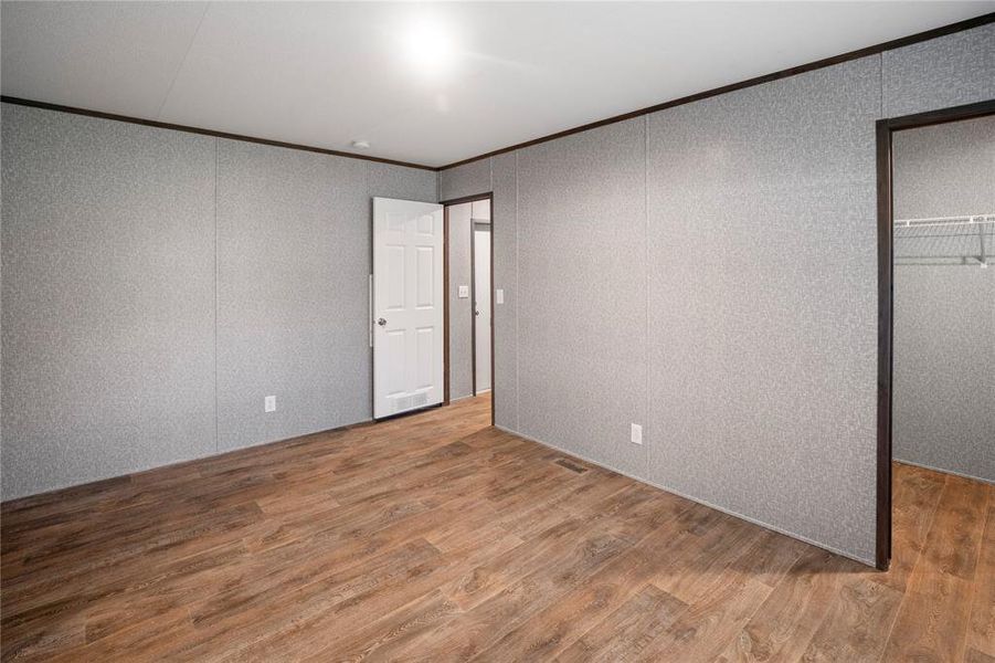 Unfurnished room with ornamental molding, wood finished floors, and a decorative wall