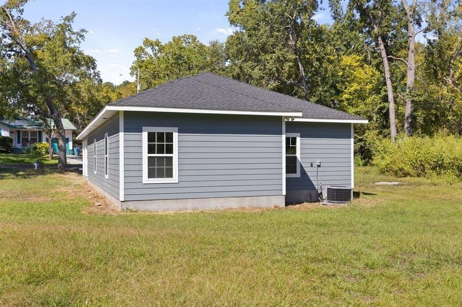 Back of house featuring a shingled roof and a lawn