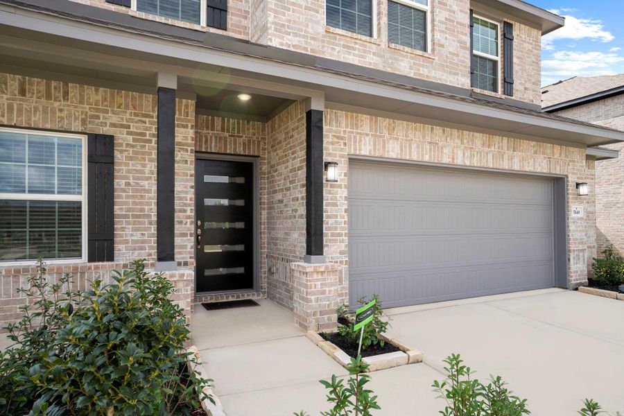 A closer look at the impressive exterior showcases the upgraded brickwork, full landscaping, and a spacious driveway leading to the 2½-car garage — perfect for extra storage or a workshop space.