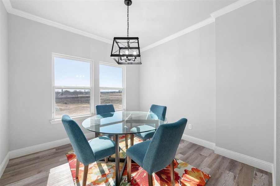 Dining area with crown molding, a chandelier, and light wood-type flooring