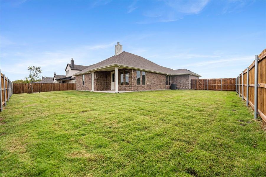 Back of house with a fenced backyard, a chimney, a patio, and brick siding Back of house with a fenced backyard, a chimney, a patio, and brick siding