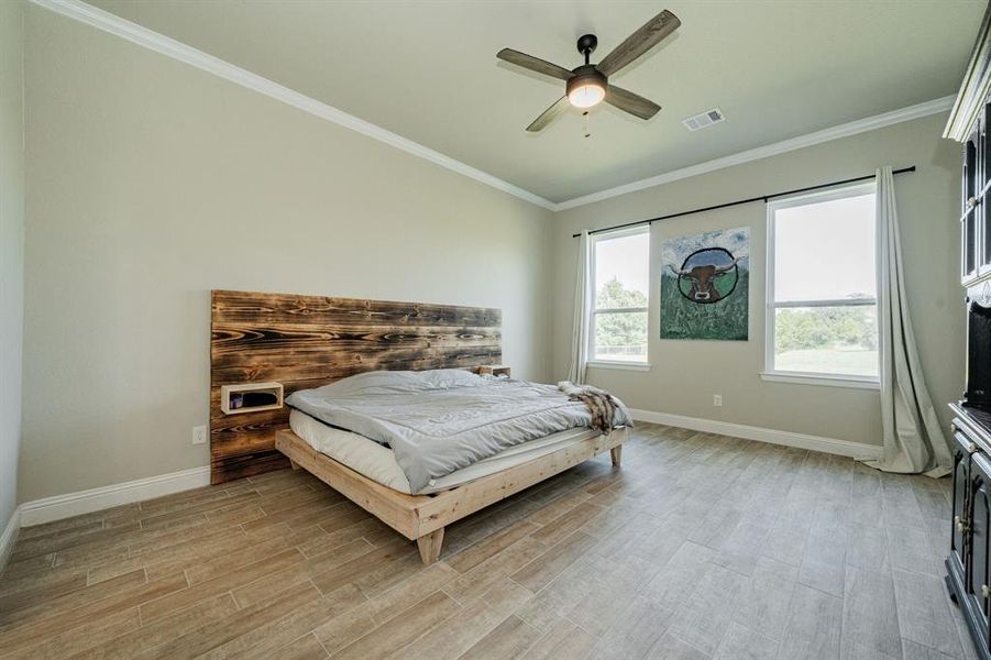 Bedroom with ornamental molding, light wood-style flooring, and a ceiling fan Bedroom with ornamental molding, light wood-style flooring, and a ceiling fan