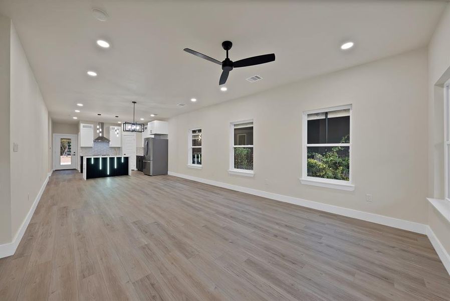 Unfurnished living room with recessed lighting, light wood-style floors, a ceiling fan, and a chandelier