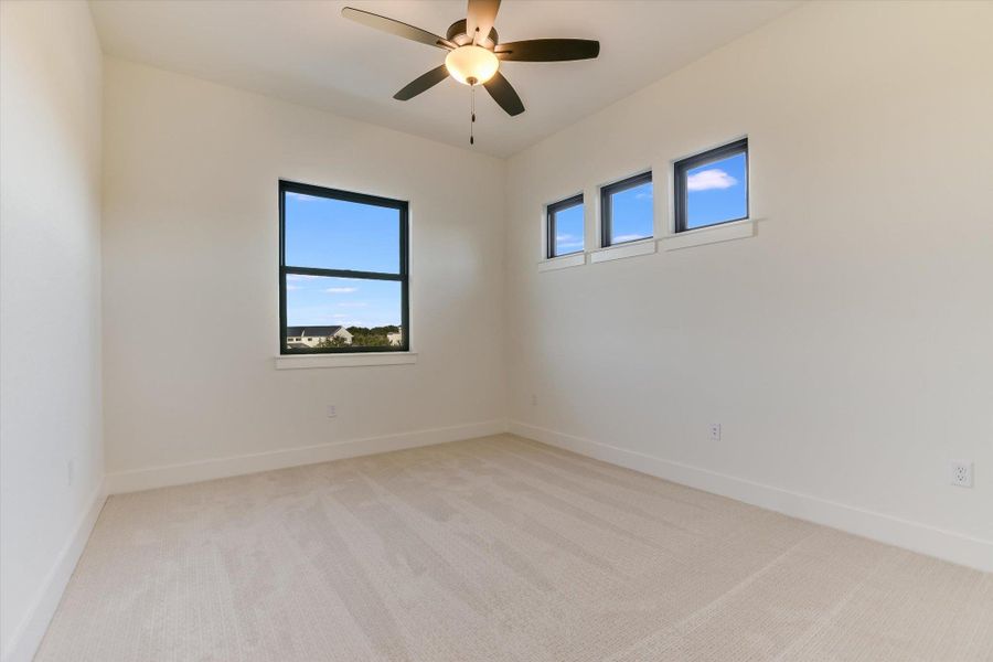 Empty room featuring light carpet, plenty of natural light, and a ceiling fan