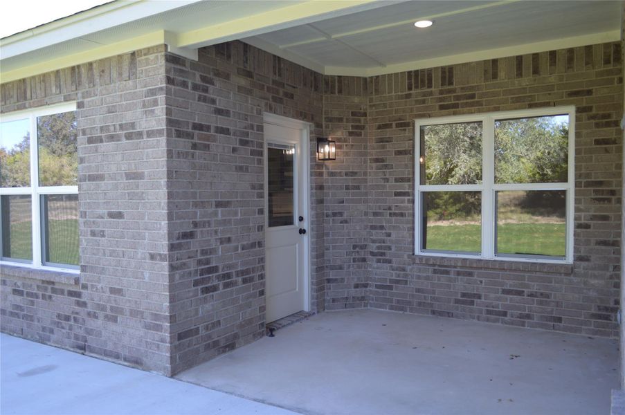 Entrance to property featuring brick siding and a patio area Entrance to property featuring brick siding and a patio area