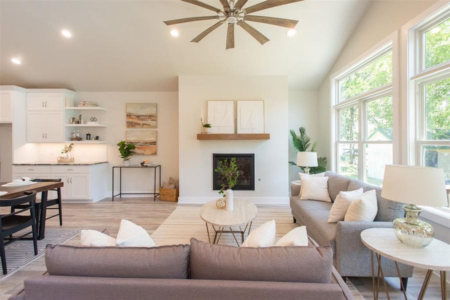 Living room with lofted ceiling, ceiling fan, and light hardwood / wood-style floors, large windows