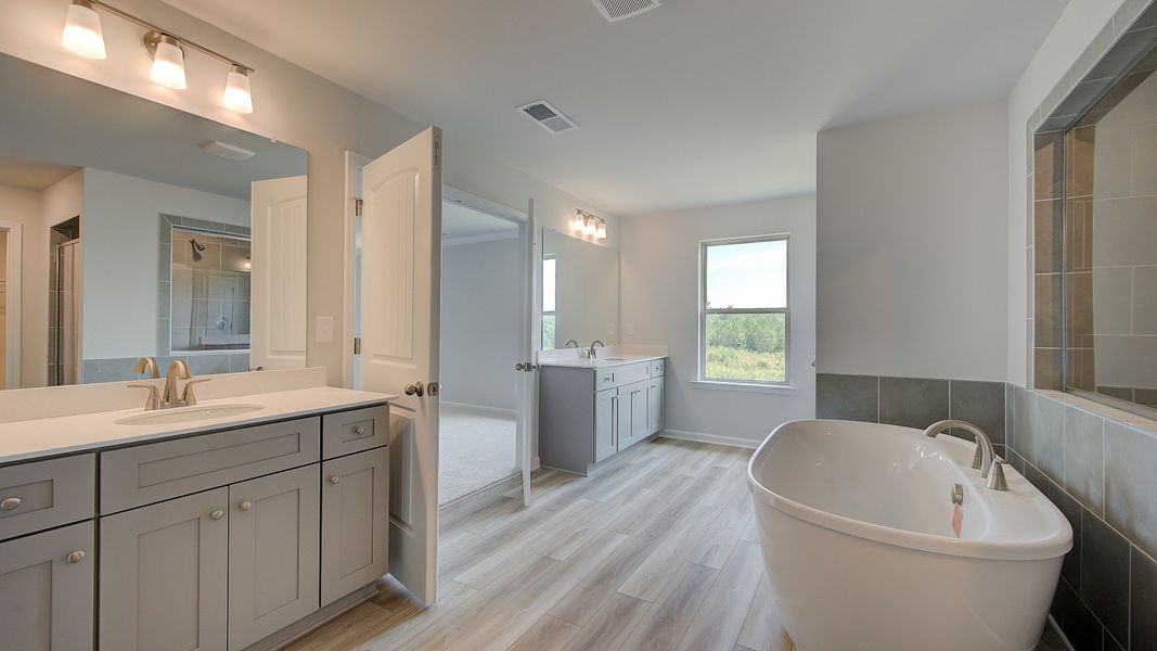 Luxury primary bath with dual vanities, freestanding tub, and neutral modern finishes in the Clarity at Brighton.