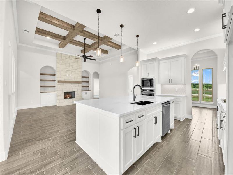 Kitchen with arched walkways, decorative light fixtures, white cabinetry, wood finish floors, and beam ceiling
