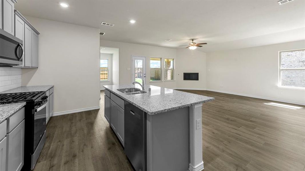 The open-concept living space features a kitchen island with a double sink, granite countertops, and a built-in dishwasher