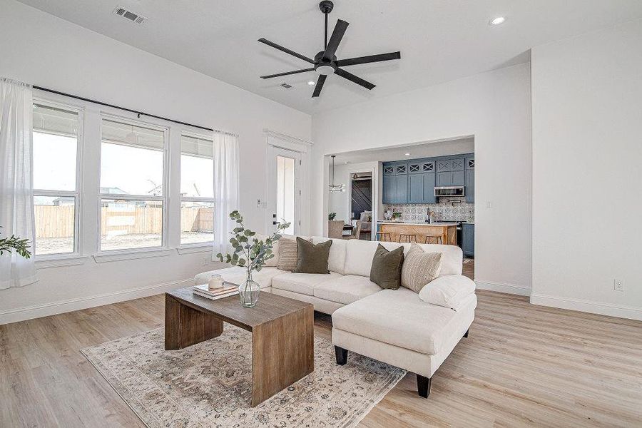 Living room with baseboards, visible vents, light wood finished floors, recessed lighting, and ceiling fan