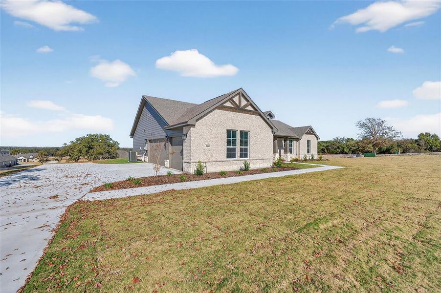 View of front facade featuring a front yard, brick siding, concrete driveway, and a garage View of front facade featuring a front yard, brick siding, concrete driveway, and a garage