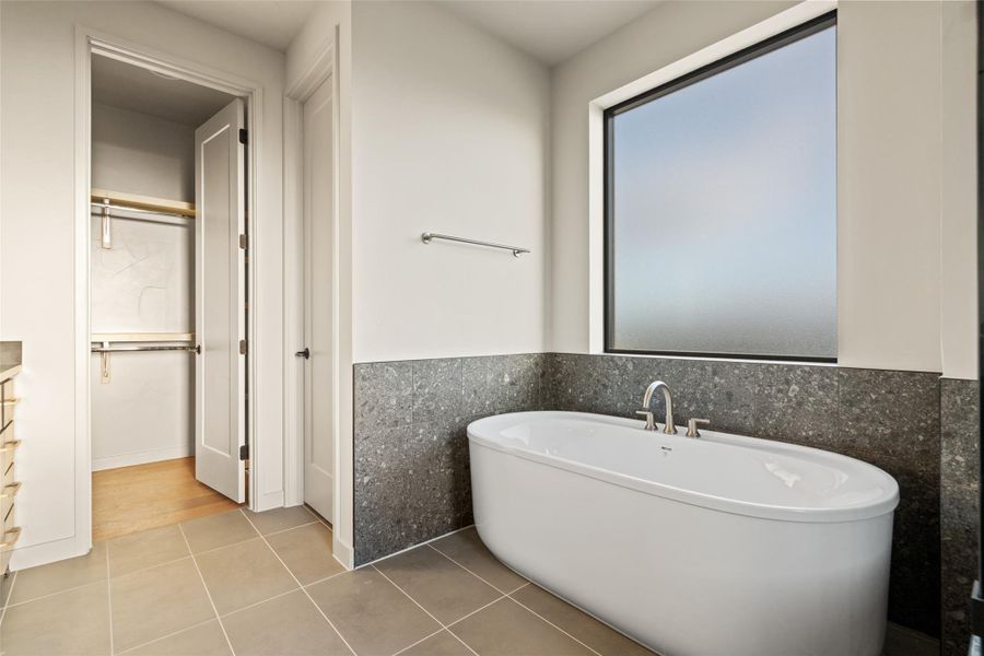 Unwind in the pristine soaking tub, set against sophisticated tiled wainscoting.