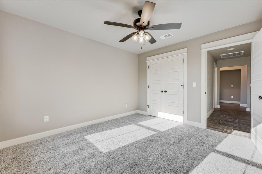 Unfurnished bedroom featuring carpet floors, a ceiling fan, and a closet Unfurnished bedroom featuring carpet floors, a ceiling fan, and a closet